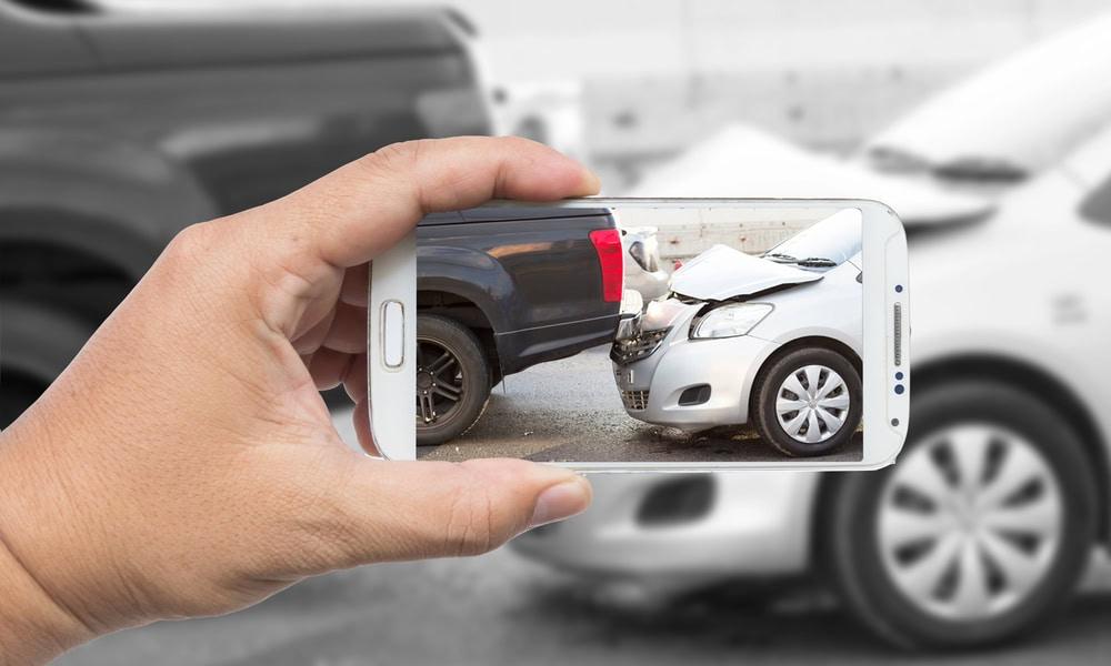 Driver using a smartphone to report a USAA car insurance claim after an accident. 